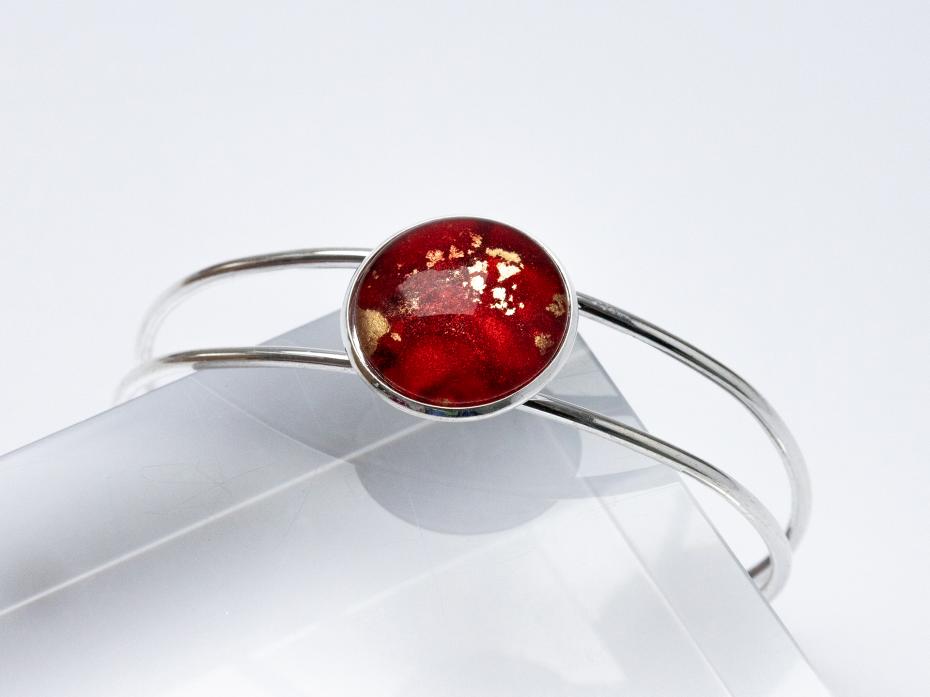 Bangle with red alcohol ink art sealed with a glass cabochon